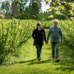 Pariskunta käsikkäin puutarhassa kävelyllä