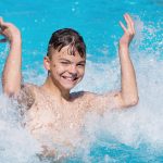 Nuori poika pärskyttää vettä vesipuistossa.