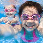 Tyttö ottaa pikkusiskon kanssa selfien veden alla.