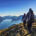 Seurue vaeltamassa vuori- ja merimaisemissa kirkkaana päivänä.