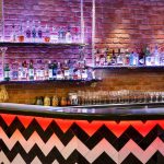 Värikäs baaritiski ja pulloja hyllyssä