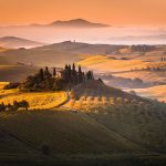 Aurinko nousee Toscanan kumpuilevalla maaseudulla.