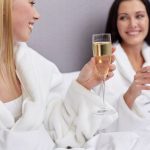 Kylpylätakkeihin pukeutuneet ystävykset kohottavat kuohuviinilaseja.