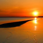 Oranssi auringonlasku rannalla.