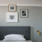 Sängyn pääty ja tauluja seinällä taustalla