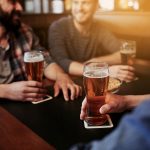 Kaveriporukka istuu iloisena pubissa oluttuopit kädessä.