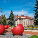 Jõhvin keskusaukio ja kaupungintalo kesäpäivänä. Edustalla isoja, punaisten marjojen inspiroimia koristeita ja istuimia.