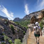 Reppuselkäinen vaeltaja kulkee aidattua vaellusreittiä.