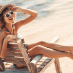 Nainen istuu rantatuolissa, taustalla rantahiekka ja meri.
