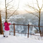 Pikkutyttö katselee Vilnia-jokea ylhäällä aidan takaa.