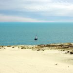 Purjevene merellä, edustalla hiekkarantaa.