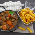 Lihapataa kauhallisessa vadissa, vieressä kori, jossa ranskalaisia.