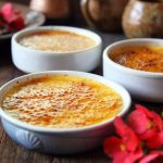 Kolme paahdettua vanukasannosta puisella pöydällä, ympärillä kukkia ja astioita.