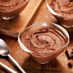 Kolme annosta suklaamoussea puisella tasolla.