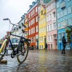 Vanha pyörä Kööpenhaminan kadulla värikkäiden rakennusten edustalla.