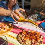 Mies kaataa öljyä mustekala-annoksen päälle.