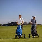 Mies ja poika työntävät golfkärryjä