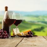 Punaviinia, rypäleitä ja juustoja. Vihreä laakso taustalla.