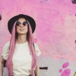 Pinkkihiuksinen nainen pinkin seinän edessä