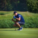 Mies tuulettaa golflyöntiä greenillä