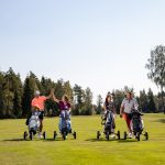 Neljä golfaria greenillä kärryjen kanssa