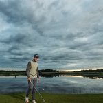 Mies golfkentällä veden äärellä