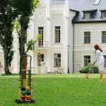 Ihmisiä pelaamassa krokettia kartanon nurmialueella.