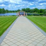 Järven rannassa olevalle huvimajalle johtava kivilaattapolku nurmikentän keskellä.