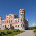 Kaunis vaaleanpunainen linnarakennus puiston keskellä kirkkaana kesäpäivänä.