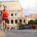 Punapaitainen mies juoksemassa kadulla, taustalla Colosseum.