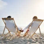 Pariskunta kansituoleissa hiekkarannalla.