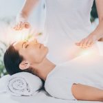 Nainen makoilee silmät kiinni reikihoidossa.