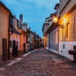 Kuja iltahämärässä, lyhtyjä palaa rakennusten seinustalla.