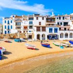 Veneitä ja valkoinen rakennus rannassa.