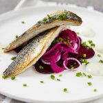 Lautaselle koostettu kala-annos, jossa paistettua kalaa ruohosipulia ja punajuurta