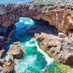 Luolamainen kivimuodostelma meren rannalla.