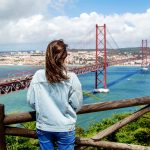 Farkkuasuinen nuori nainen katselee siltaa.