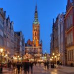 Jouluvalaistua katunäkymää Gdanskissa, taustalla kellotorni.