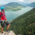 Kiipeilijä ihailee maisemia korkealla kalliolla.