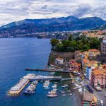 Veneitä, värikkäitä taloja, jylhää rantamaisemaa Sorrentossa sinisen meren rannalla
