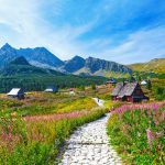 Kivinen polku kohti rakennuksia kauniissa vuoristomaisemissa.