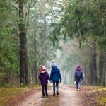 Lämpimästi puettuja lapsia metsätiellä.