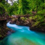 Puinen silta turkoosin joen yllä.