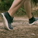 Lähikuva kävelijän jaloista hiekkapolulla.