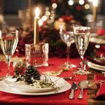 Jouluinen kattaus punaiselle pöytäliinalla kuohuviinilasien kanssa