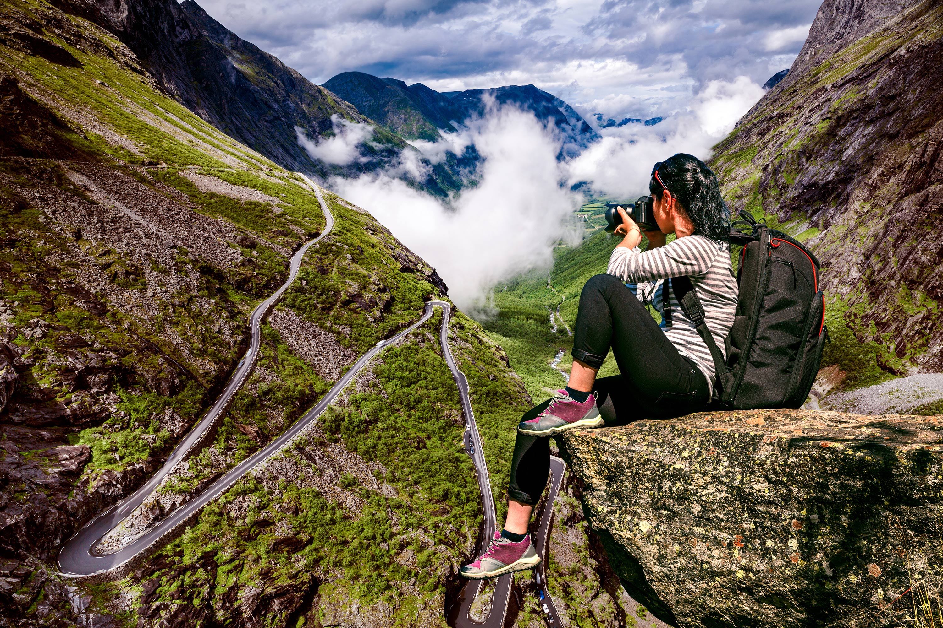 Nature photographer tourist with camera shoots while standing on top of the mountain.