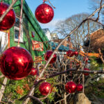 Punaisia palloja vihreän rakennuksen ja kasvillisuuden edessä.