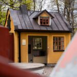 Keltainen puutalo puistossa.