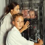 Perhe ratkomassa pakohuoneen salaisuuksia oven molemmilla puolilla.