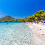 Ihmisiä rannalla kirkkaana päivänä.